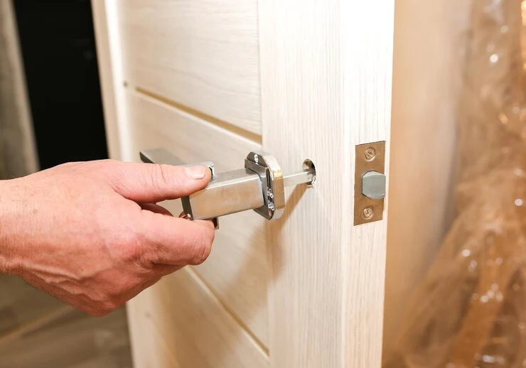 En mann installerer dørhåndtakene og utfører vedlikeholdsarbeid.